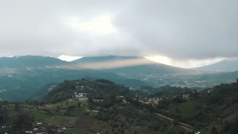 Vista-Aérea-De-Drones-De-Un-Hermoso-Valle-Durante-Una-Puesta-De-Sol-Nublada-Con-Rayos-De-Dios,-Paisaje-Volcánico-En-Guatemala