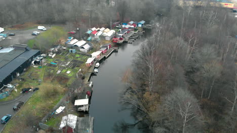 Aerial-shot-of-river-with-tiny-sheds-and-boats-on-autumn-day