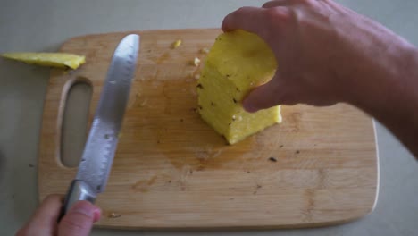 First-Person-POV-White-Man-Cutting-a-Pineapple-on-a-Cutting-Board