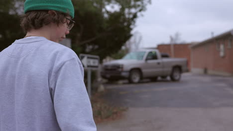 Teenage-boy-with-skateboard-walks-towards-an-alley-in-slow-motion
