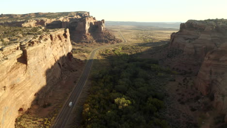 Drone-footage-of-RV-driving-along-road-between-two-canyons,-on-an-epic-American-roadtrip-in-utah-near-canyon-lands-national-park