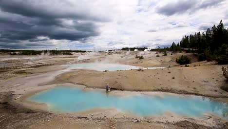Stunning-view-of-geothermal-geysers-and-hot-springs-with-steam-clouds-rising-and-turquoise-ponds-on-a-cloudy-overcast-day-at-Yellowstone-National-Park,-Wyoming,-USA