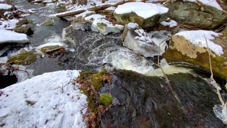 A-pristine-mountain-stream-running-through-a-snowy-forest-in-winter,-in-the-appalachian-mountains