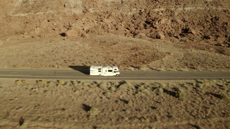 Sideview-drone-footage-of-RV-driving-along-road-on-American-road-trip-in-the-desert-in-Utah