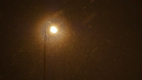 Nieve-Cayendo-A-La-Luz-Amarilla-De-La-Lámpara-De-La-Calle-Por-La-Noche