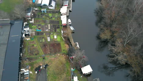 Top-down-shot-of-shed-and-small-vegetable-patches-along-a-calm-river
