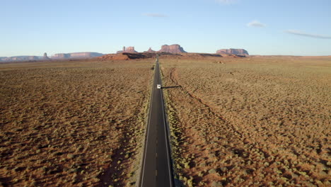 Drone-footage-of-RV,-motorhome-driving-along-iconic-forest-Gump-highway-in-Monument-Valley,-Utah-on-American-road-trip
