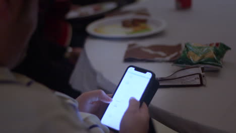 Close-up-shot-of-male-person-typing-and-swiping-on-the-smartphone-after-dinner-in-restaurant