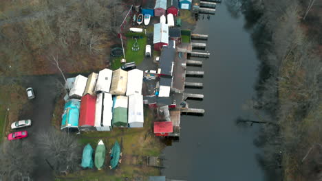 Aerial-shot-of-tiny-sheds-along-a-river-on-a-humid-winter-day