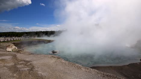 Stunning-panning-view-across-huge-geothermal-geyser-with-dense-steam-cloud-rising-at-Yellowstone-National-Park,-Wyoming,-USA