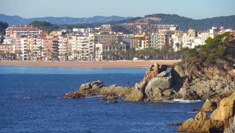 Beach-rock-paradise-Lloret-de-Mar-european-beach-in-mediterranean-spain-white-houses-calm-sea-turquoise-blue-begur-costa-brava-ibiza