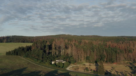 Aerial-Shot-Of-An-Agricultural-Farm-Surrounded-By-Pristine-Forest-In-Fall-At-Sunset