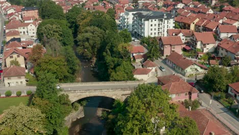 Luftaufnahme-Von-Autos,-Die-An-Der-Steinbrücke-In-Der-Stadt-Ivanjica-In-Serbien-Vorbeifahren