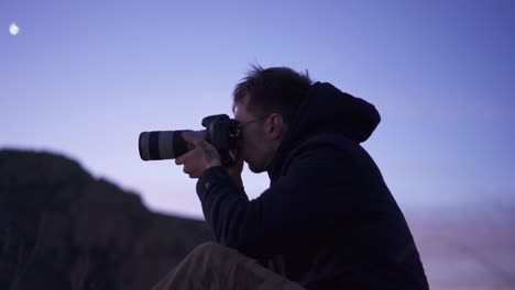 Male-photographer-taking-photographs-on-mountain-peak-hike-at-sunrise