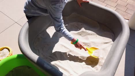 A-boy-using-yellow-shovel-scooping-ou-sand-into-a-bucket