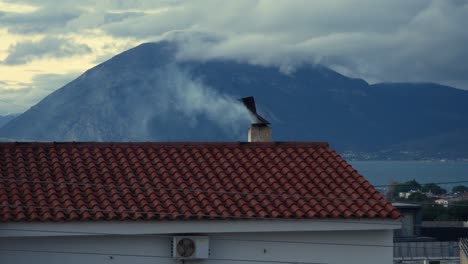 Smoke-coming-out-of-a-chimney-rotating-rooster-of-a-tiled-roof-on-a-cold-winter-day