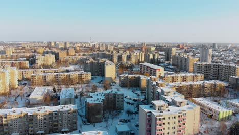 Aerial-view-of-apartments-houses-in-winter,-snowy-environment,-sunny-day,-flying-above-apartments-round,-parallax,-Lithuania
