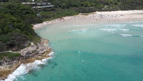 Turistas-Nadando-Y-Relajándose-En-La-Playa-Con-Un-Exuberante-Follaje-En-La-Playa-De-La-Cabecera-Del-Cilindro-En-Point-Lookout,-Australia