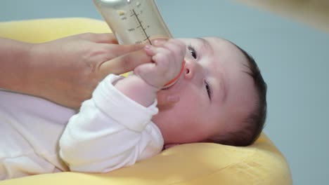 Lovable-Baby-Lying-While-Bottle-Feeding-By-Her-Mother-At-Home