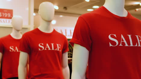 Close-up-of-mannequins-in-red-t-shirts-with-the-words-sale-in-retail-shop