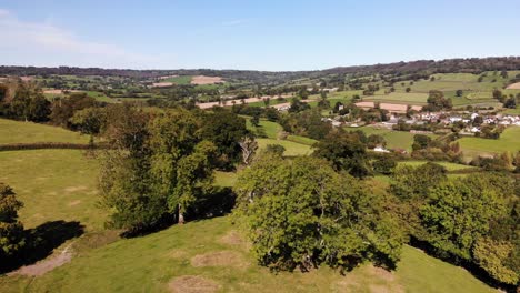 Aerial-backward-shot-looking-over-trees-and-beautiful-East-Devon-Countryside-England