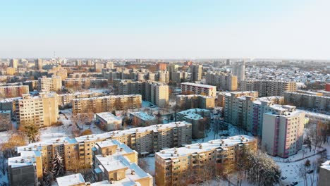 Aerial-view-of-apartments-houses-in-winter,-snowy-environment,-sunny-day,-flying-above-apartments-houses-straight,-zoom-in