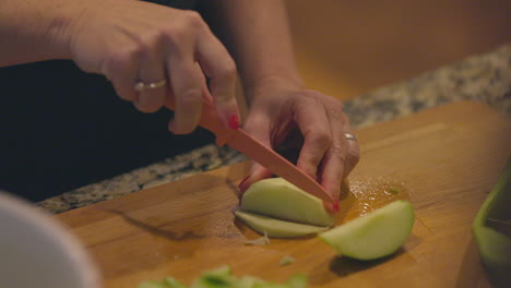 A-woman-slices-a-green-apple-into-thin-slices-in-slow-motion