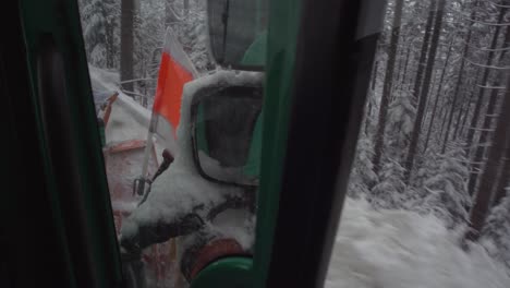 View-out-of-drivers-cabin-of-snow-plow-clearing-snowy-road,-close-up-of-equipement-during-plowing