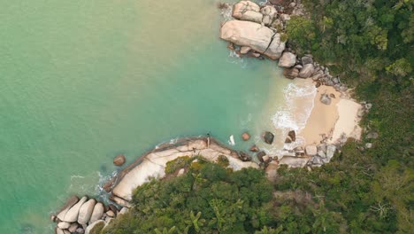 Aerial-top-down-view-of-tropical-beach-with-clear-water-and-big-rocks-in-Bombinhas,-Santa-Catarina,-Brazil