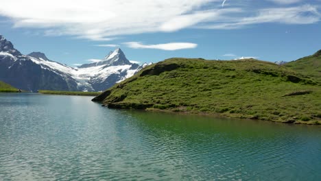 Espectacular-Toma-Aérea-Reveladora-Del-Lago-Azul-De-La-Montaña-En-Los-Alpes-Suizos-Con-Un-Espectacular-Telón-De-Fondo-De-Picos-Montañosos-Cubiertos-De-Nieve,-Bachalpsee-Grindelwald-Primero,-Suiza