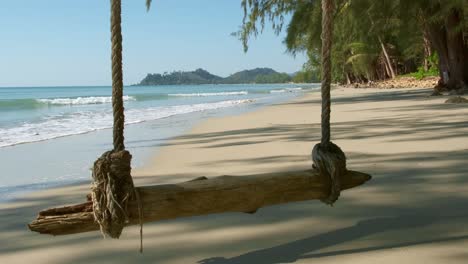Tropischer-Weißer-Sandstrand-Mit-Seilschaukel,-Kleinen-Wellen-Und-Tropischen-Bäumen