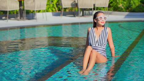 Beautiful-Fit-Asian-Girl-Enjoys-sitting-in-the-swimming-Pool-SLOMO