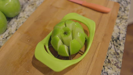 push-towards-a-freshly-sliced-apple-sitting-in-a-slicer-on-a-cutting-board-in-a-kitchen