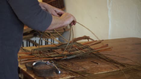 Ein-Korbflechter-Formt-Und-Verwebt-Die-Holzstäbe,-Während-Er-Von-Hand-Einen-Traditionellen-Walisischen-Korb-Herstellt