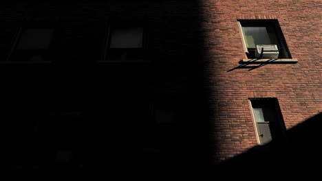 Schatten-An-Der-Wand-Des-Backsteingebäudes-Mit-Fenstern,-Wenn-Das-Sonnenlicht-Verschwindet