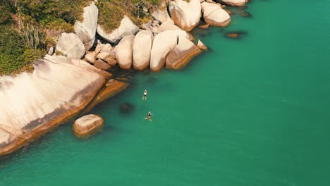 Swimming-in-turquoise-color-water-sea-near-big-rocks