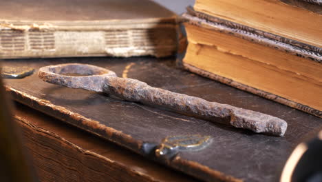 Magischer-Alter-Schlüssel-Und-Historische-Bücher-Auf-Dem-Tisch-In-Wechselndem-Licht