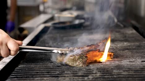Grilling-Fresh-Marinated-Lamb-Rib-Chops-Over-The-Fire,-Flipping-With-Tongs---close-up