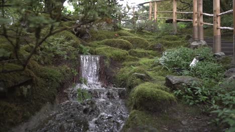 Tracking-out-shot-of-a-waterfall-and-mossy-rocks-in-a-Japanese-garden