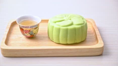 Chinese-moon-cake-green-tea-flavour-with-tea-on-wood-plate