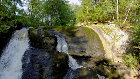 Rising-aerial-footage-showing-a-fresh-water-cascade-flowing-through-the-rocks-in-the-middle-of-dense-forest