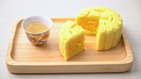 Chinese-moon-cake-custard-flavour-with-tea-on-wood-plate