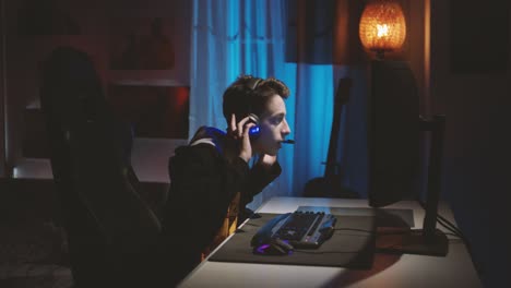 Teenage-boy-wearing-headphones-playing-an-online-computer-game,-communicating-with-players