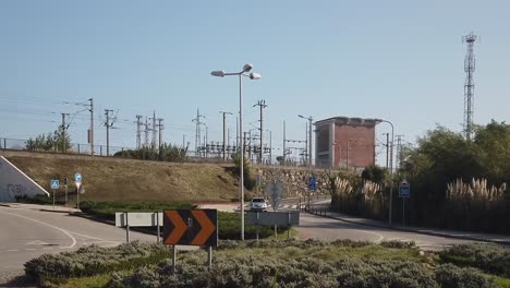 Blick-Auf-Die-Energiestation-Und-Einen-Kreisverkehr-Mit-Fahrenden-Autos-Und-Blauem-Himmel-Im-Hintergrund