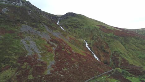 Idyllic-Snowdonia-mountain-range-Aber-falls-waterfalls-national-park-aerial-view-valley-pull-back-pan-left
