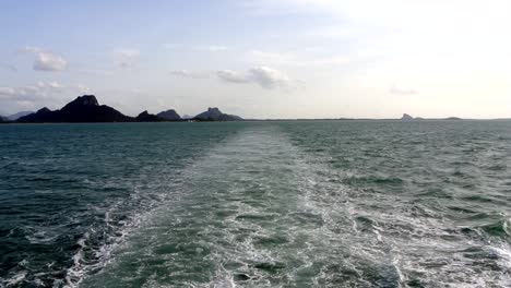 A-view-off-the-back-of-a-ship-over-looking-the-sea-with-tropical-islands-in-background
