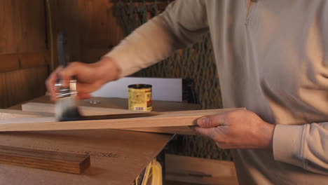 Close-up-footage-of-man-staining-plank-of-wood-in-a-wood-workshop