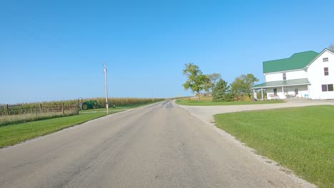 Pov-Fahrt-Auf-Der-Ländlichen-Kreisstraße-Vorbei-An-Reifenden-Feldern,-Landwirtschaftlichen-Geräten-Auf-Den-Feldern-Und-Höfen-Im-Ländlichen-Iowa-An-Einem-Sonnigen-Frühen-Herbsttag---In-Der-Nähe-Von-Kalona,-Iowa,-USA