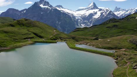 Espectacular-Vista-Aérea-Del-Lago-De-Montaña-Azul-En-Los-Alpes-Suizos-Con-Un-Espectacular-Telón-De-Fondo-De-Picos-Montañosos-Cubiertos-De-Nieve,-Bachalpsee-Grindelwald-Primero,-Suiza
