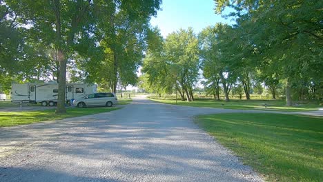 Sunny-day-in-Iowa-with-POV-slowly-driving-thru-a-campground-with-only-a-few-guests-in-late-summer
